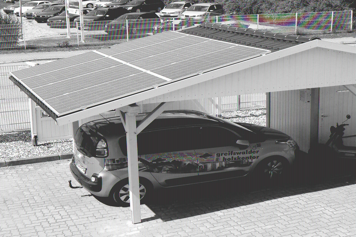 Weiß lackiertes Holzcarport, auf dessen Dach acht Solarpanels montiert wurden. Unter dem Carport parkt ein Auto in einem knalligen Grünton.